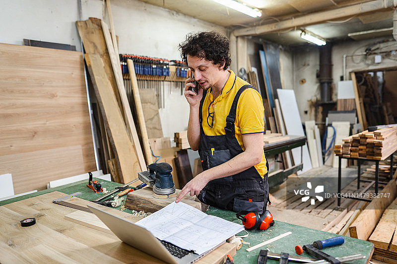 木匠在木工车间工作时正在打电话图片素材