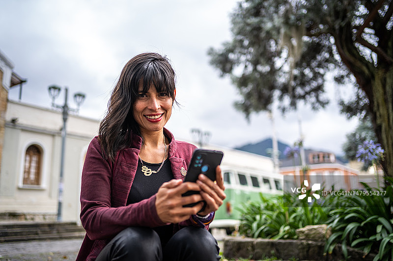 一个中年妇女在城市里使用手机的肖像图片素材