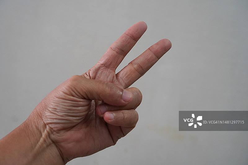 拉近亚洲女性的手在剪刀的手势，第二，胜利的手势，标志手指手臂和手孤立在一个白色背景复制空间符号图片素材
