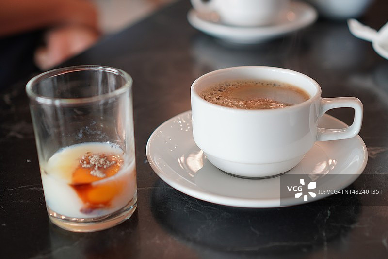半熟的鸡蛋放在玻璃杯里，咖啡放在木桌上图片素材