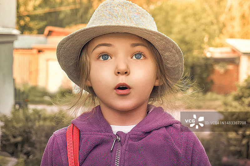 一个女孩穿着羊毛外套，戴着帽子，看起来很惊讶，夏天阳光明媚，适合散步和旅行图片素材