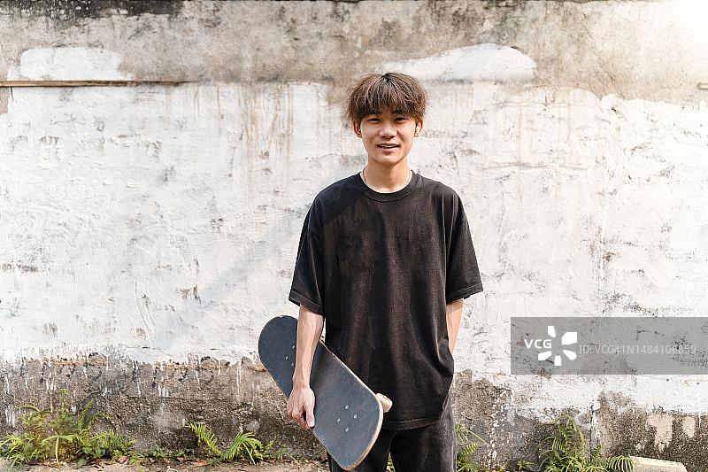 一个快乐的年轻人在路上玩滑板图片素材