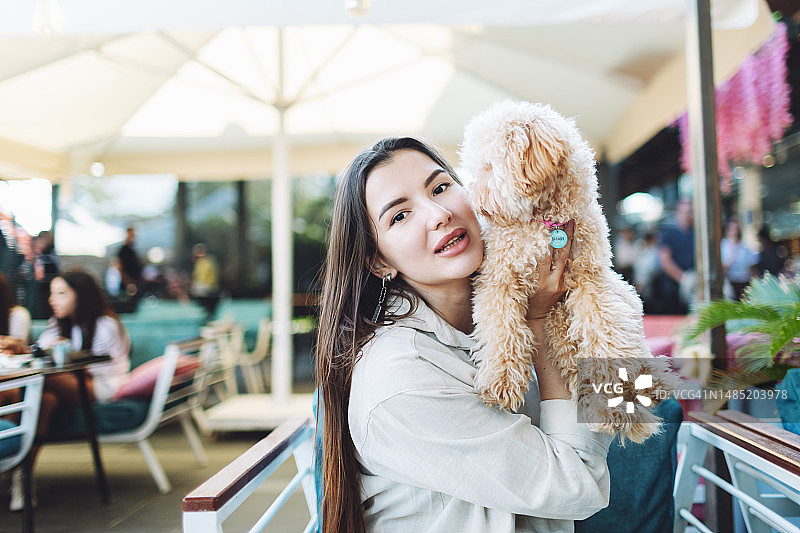 年轻的成年女子和她的小狗坐在咖啡馆里图片素材