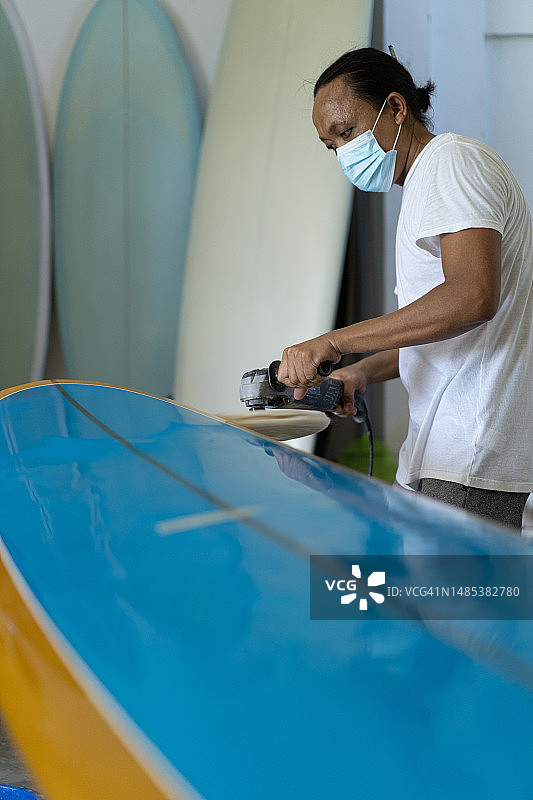 男子修理冲浪板，双手靠近，冲浪板车间在巴尔图片素材