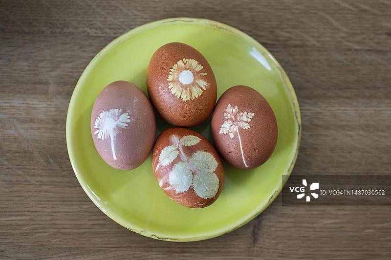 四个复活节彩蛋用洋葱皮和花在一个盘子上，花印刷，斯图加特，巴登-符腾堡州，德国图片素材