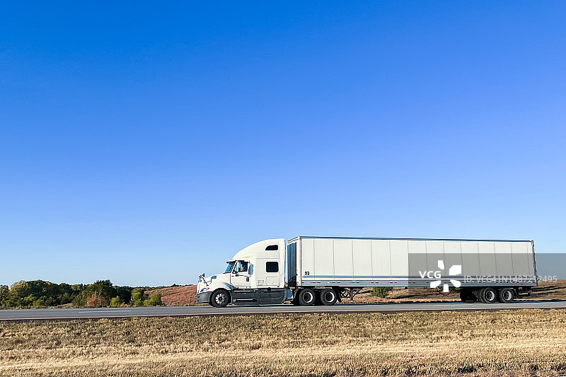 白色传统驾驶室前半卡车行驶在70号州际公路西横穿堪萨斯州在一个阳光明媚的日子图片素材
