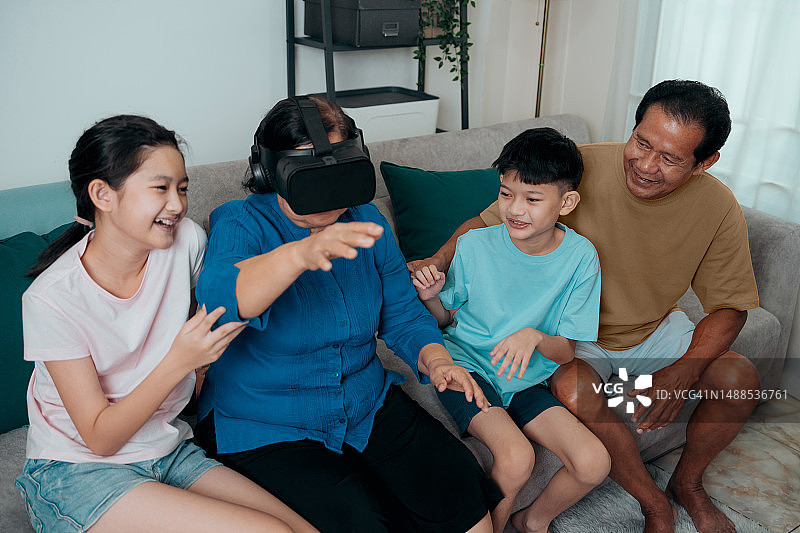 奶奶和孙子在家里玩VR头盔增强现实技术。虚拟现实的虚拟世界。图片素材