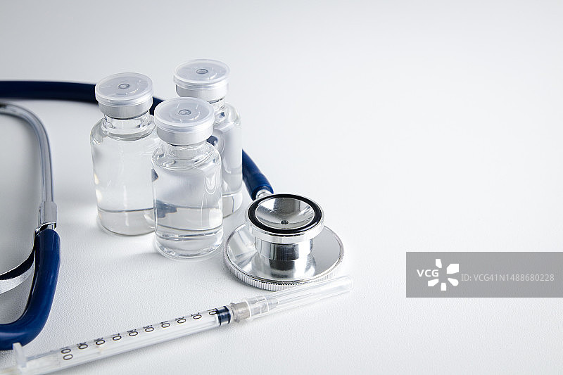 带有注射器和听诊器的防病毒疫苗瓶放置在白底，用于冠状病毒疫苗的概念，或COVID-19医院医疗服务复制空间图片素材