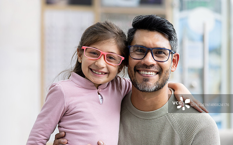 快乐的父亲和女儿在验光店试眼镜图片素材