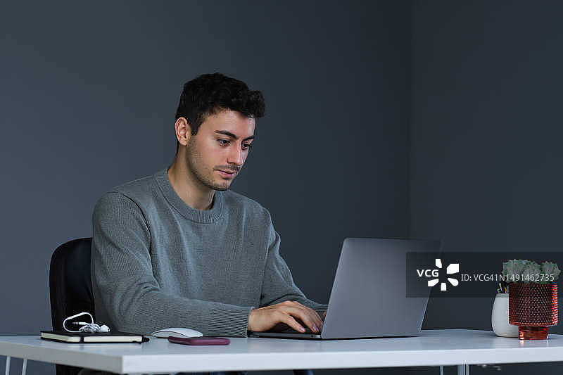 一位白人年轻人的前视图，工作重点是用笔记本电脑解决IT问题图片素材