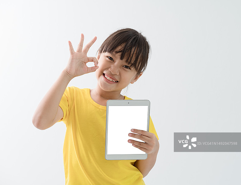 亚洲孩子拿着智能手机模型，在白色背景上显示ok的标志。图片素材