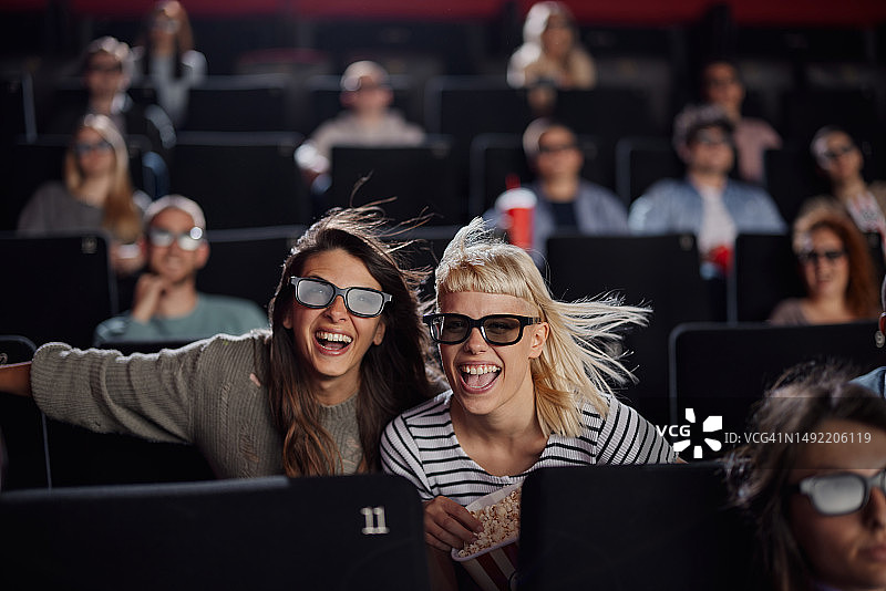 快乐的女性朋友在电影院享受3D电影。图片素材