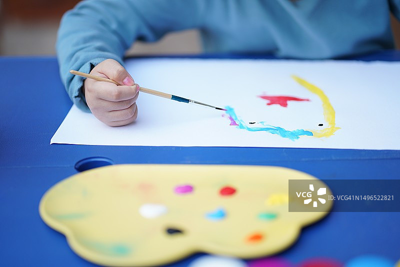 小女孩手握画笔显示水彩调色板图片素材