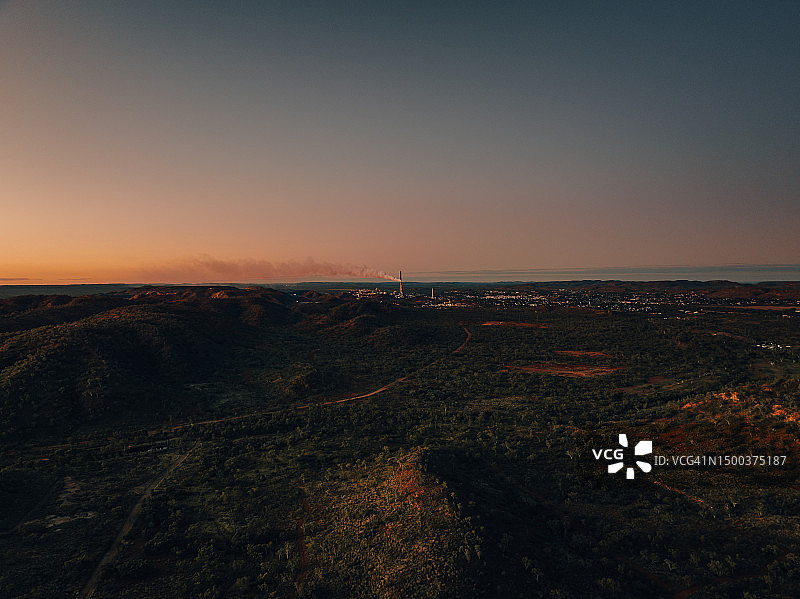 远处的无人机在日落时拍摄，显示烟雾从澳大利亚昆士兰州的伊萨山发电厂升起图片素材