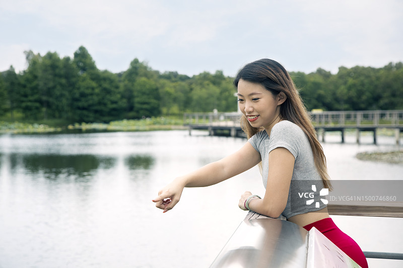 一只年轻的亚洲雌性正在触摸并指着湖面图片素材