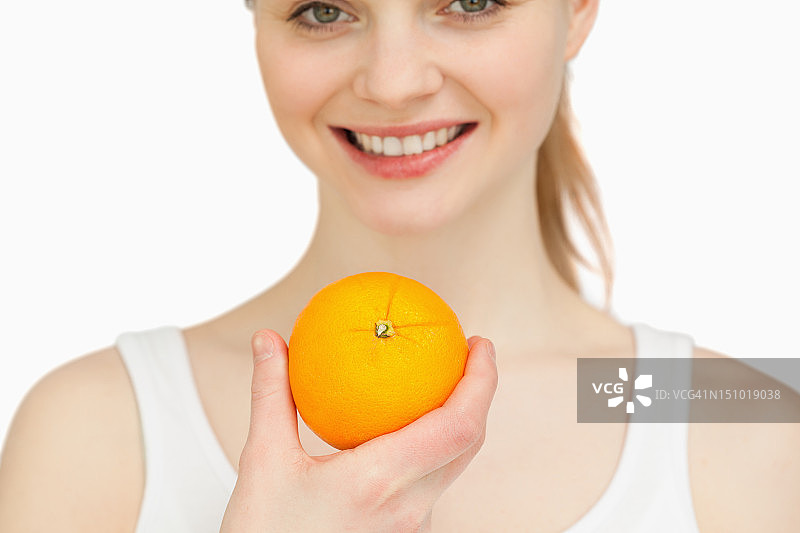 一个女人的近距离持有一个橙子，而微笑图片素材