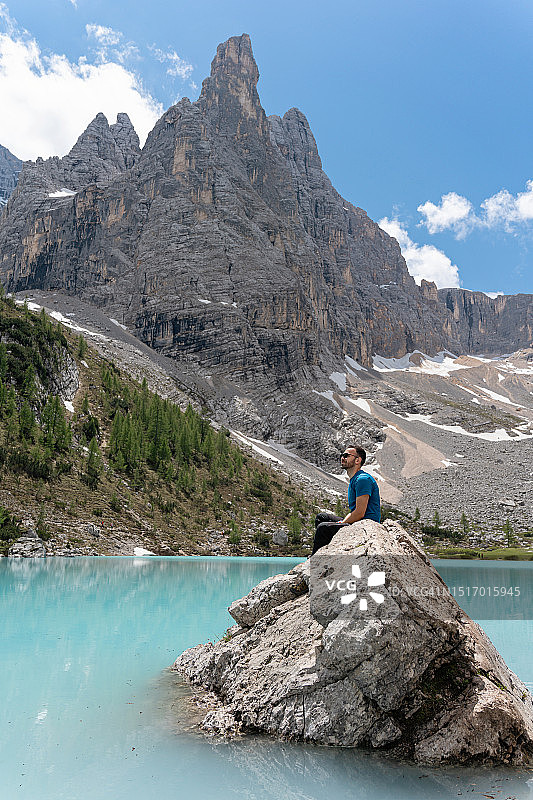 一名白人男子坐在岩石上欣赏蓝绿色的索拉皮斯湖图片素材