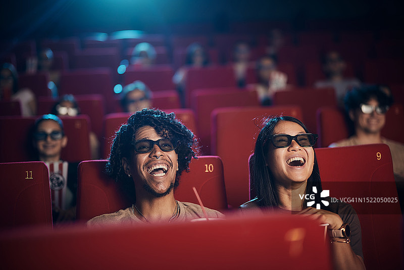 一对快乐的夫妇在电影院享受3D电影。图片素材