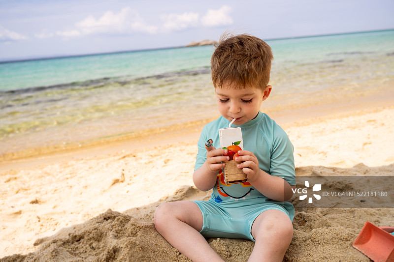 小男孩在海滩上喝果汁图片素材
