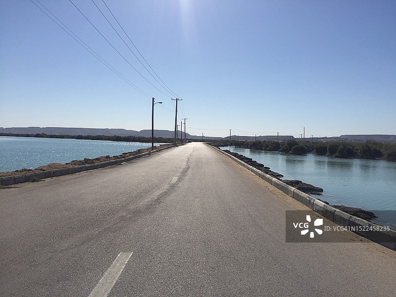 伊朗，清朗的天空衬托着空旷的湖边道路图片素材