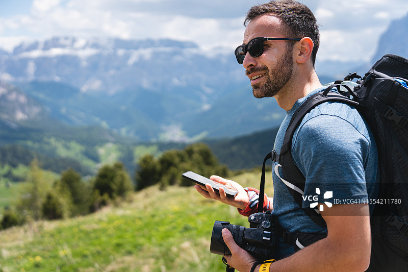 男徒步旅行者一边用手机，一边欣赏白云石的景色图片素材