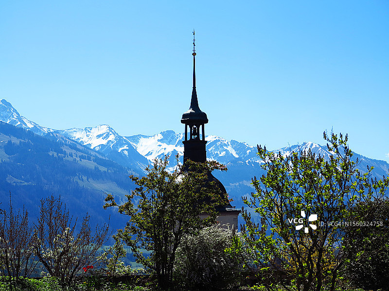 格鲁耶尔村教堂的钟楼，背景是瑞士阿尔卑斯山图片素材