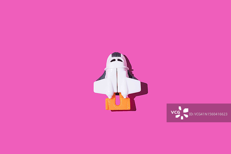 粉红色背景的玩具飞船。太空探索的概念，愿望，发射，星星，宇航员和梦想。图片素材