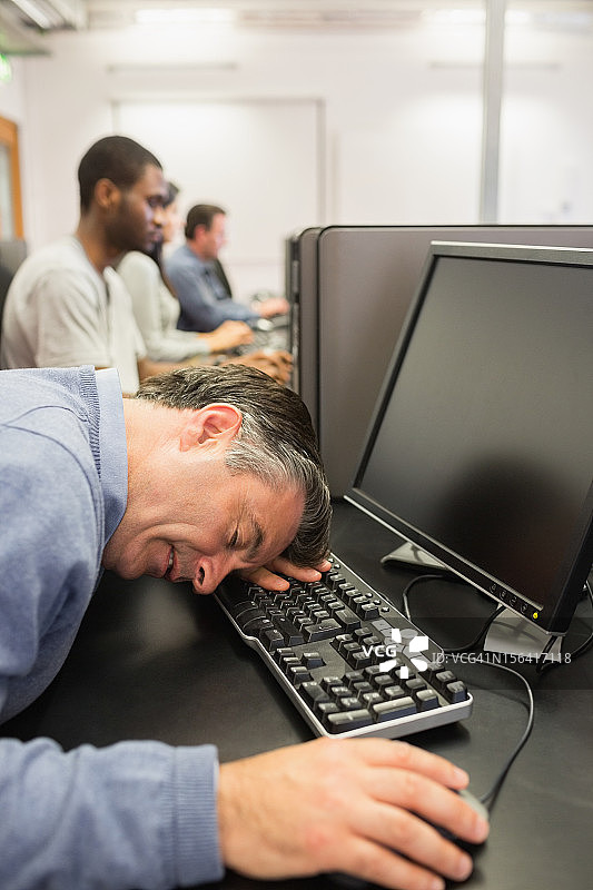 电脑课上一个在键盘前睡觉的人图片素材