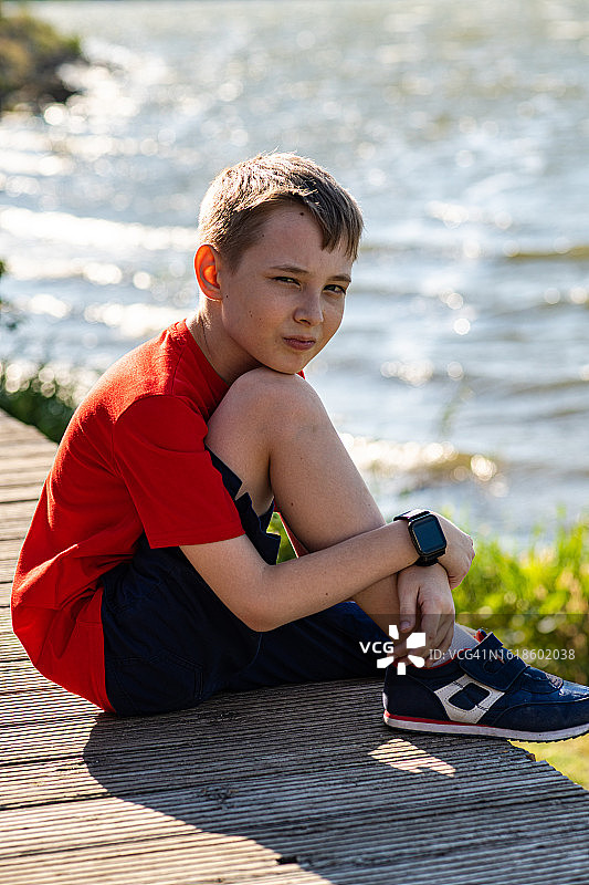 一个夏天坐在湖边的男孩的肖像图片素材