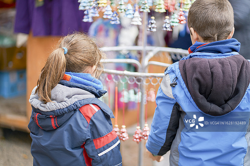 两个穿着冬衣住在一起的孩子在工艺品市场看纪念品。图片素材