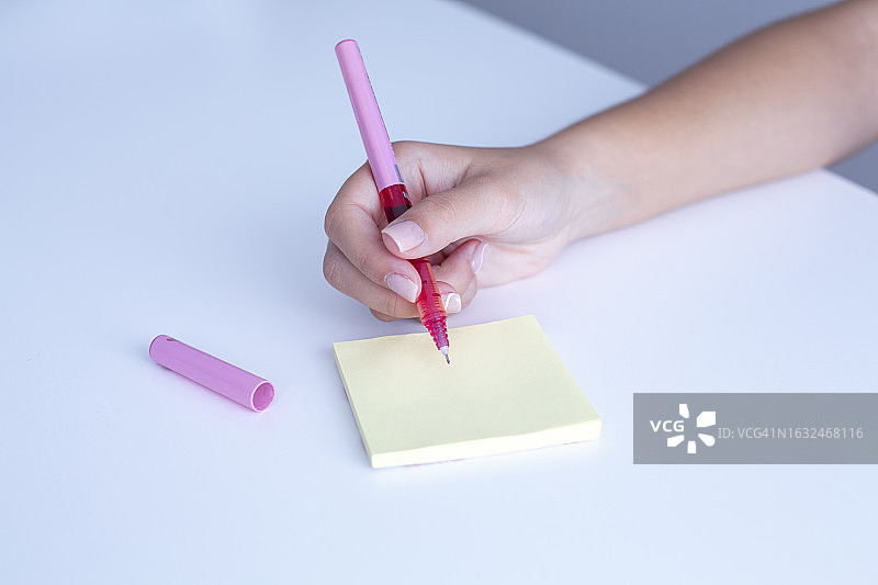 女孩用粉红色的笔在便签上写字图片素材