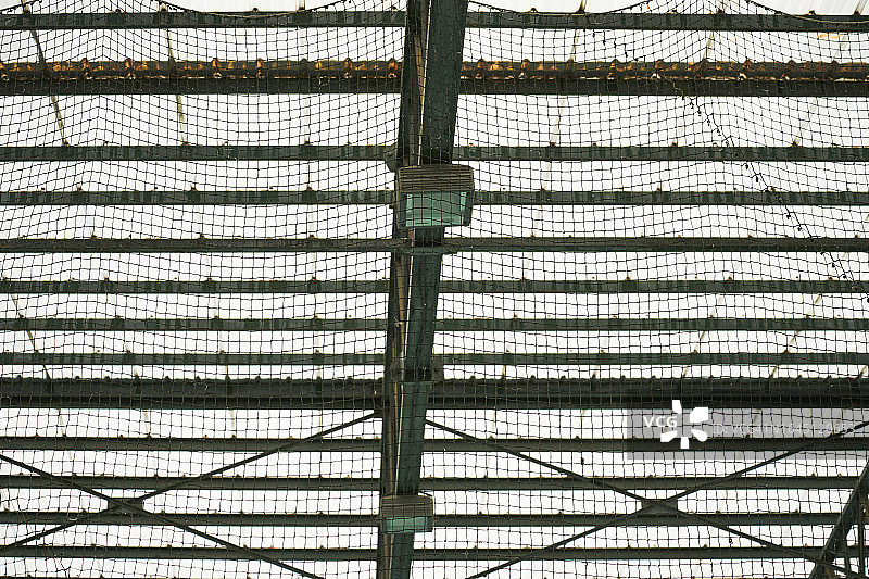 一个体育综合体的屋顶，有悬挂的网和半透明的天花板，让光线进入。图片素材