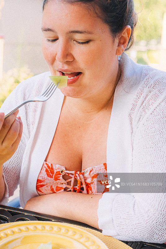 吃着一片蜜瓜的年轻女子图片素材