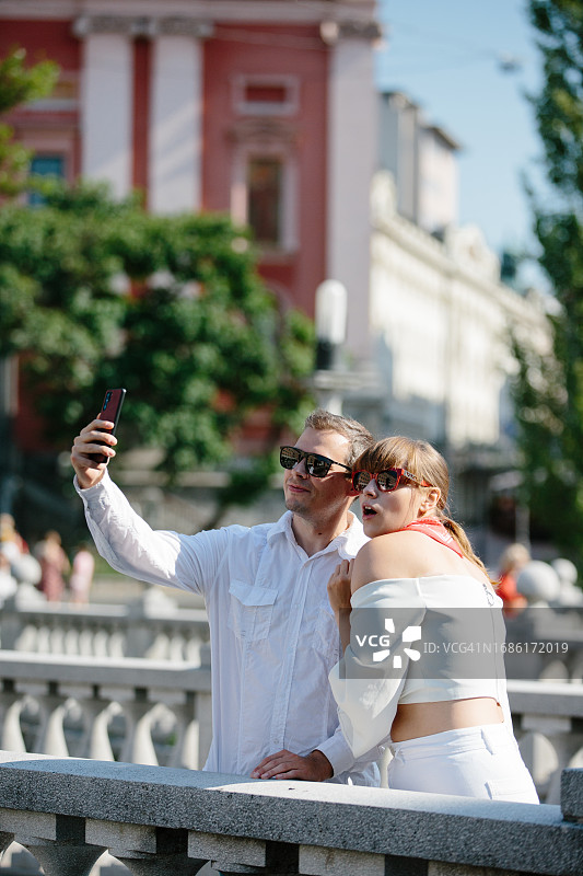 千禧一代夫妇在市中心散步，用手机拍照图片素材
