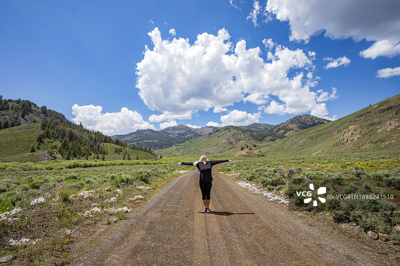 美国，爱达荷州，太阳谷，一位老妇人站在山路上，伸开双臂图片素材
