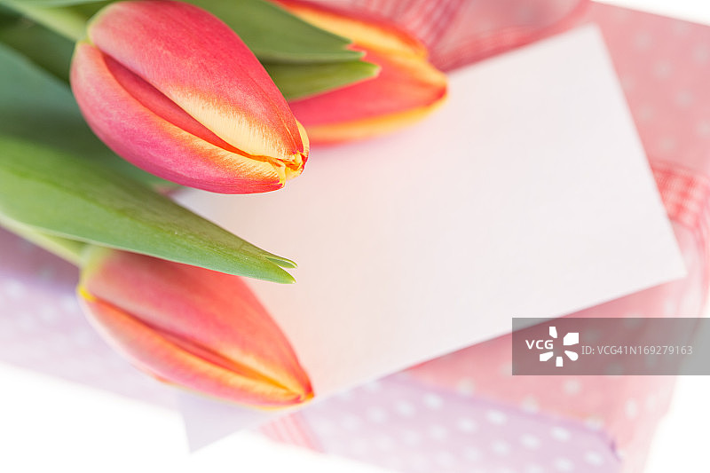 粉红色和黄色的郁金香放在粉红色包装的礼物和空白卡片上图片素材
