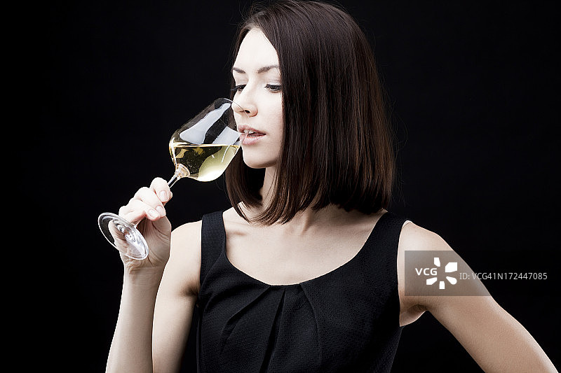 年轻漂亮的女人拿着一杯白葡萄酒图片素材