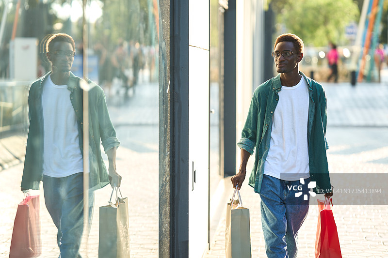 一名非洲男子在商业街拎着购物袋图片素材