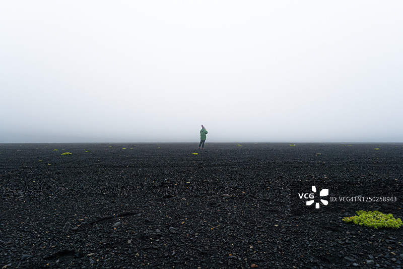一个女人的剪影拍摄冰岛火山沙滩上神秘的薄雾，孤独地漫步在冰岛火山沙滩上。图片素材