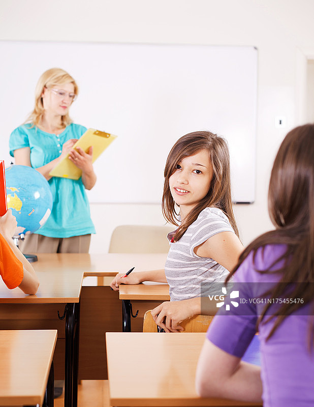 美丽的少女坐在教室里，对着镜头。图片素材