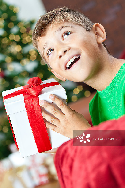 小男孩猜测并摇动他的圣诞礼物图片素材