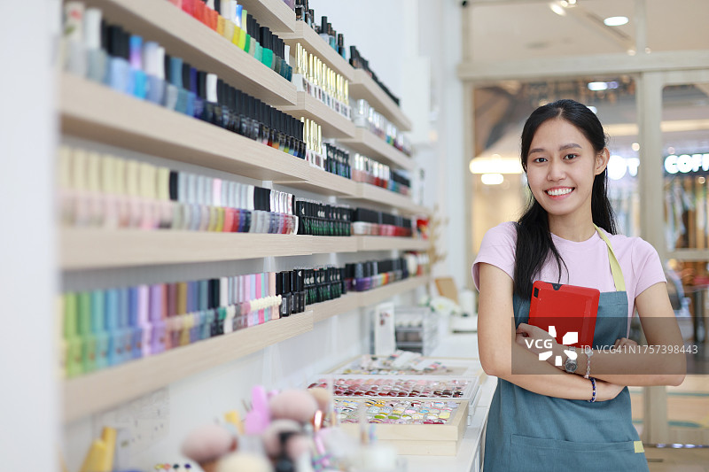 一个开朗自信的年轻亚洲女小企业主站在她的美甲店的肖像图片素材