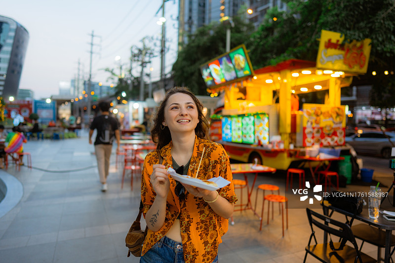 度假期间，一名女子在曼谷夜市吃泰国煎饼(roti)图片素材