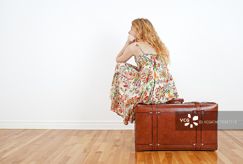 一个女孩坐在古董手提箱上，期待着旅行图片素材