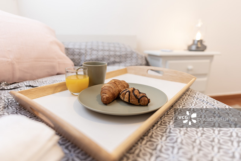 早餐是咖啡，果汁和羊角面包放在床上图片素材