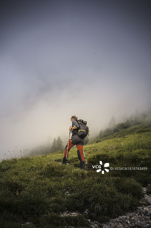 徒步旅行者走在通往山顶的浓雾小路上图片素材