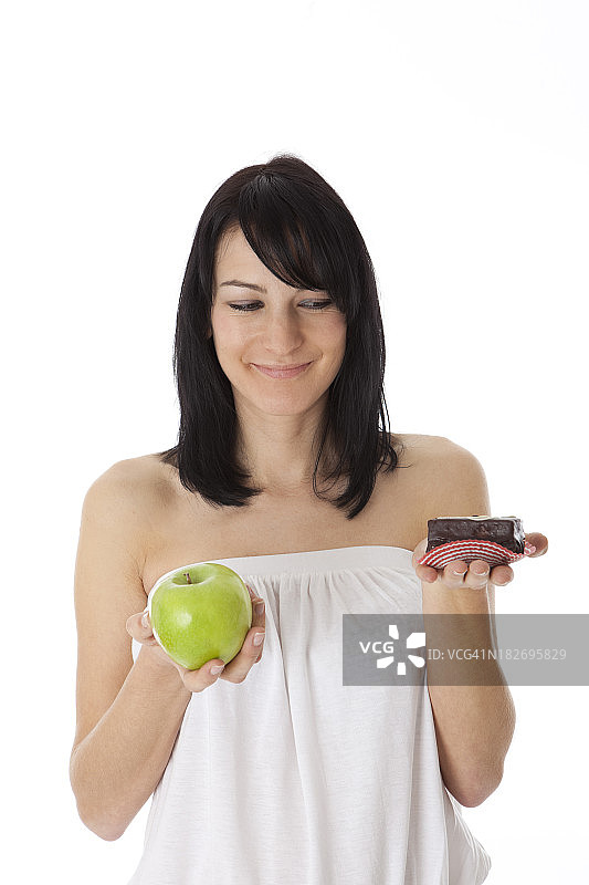 年轻女子拿着绿苹果和甜巧克力蛋糕图片素材