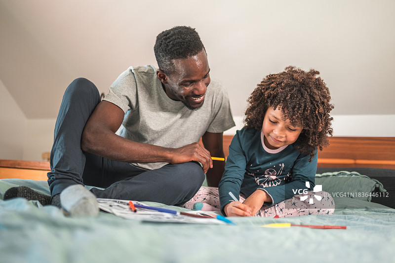 微笑的美国黑人男子和小儿子一起玩涂色图片素材