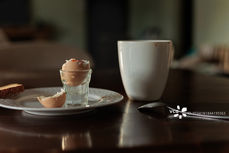 黑色木桌上的极简主义早餐。正餐是咖啡、烤面包和软鸡蛋。图片素材