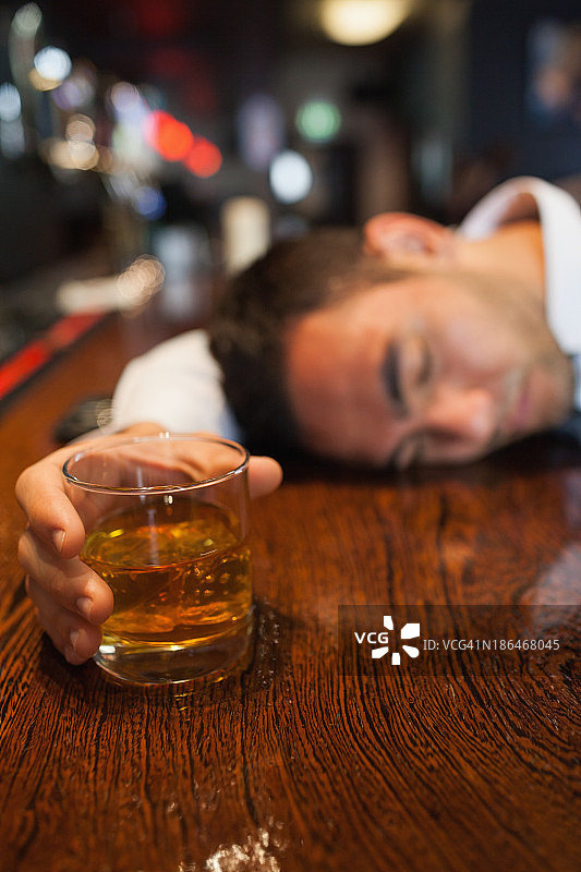 酒醉的商人拿着威士忌躺在柜台上图片素材